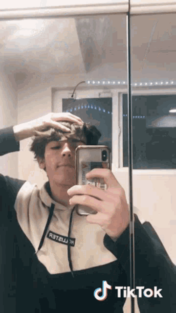 a young man is taking a picture of himself in a mirror with a tiktok watermark