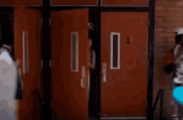 a young man with a backpack is walking out of a door .