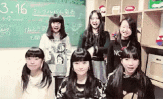 a group of young girls are posing for a picture in front of a chalkboard with the date 3.16 on it .