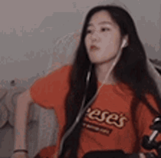 a woman is wearing a reese 's t-shirt and headphones while sitting in a chair .