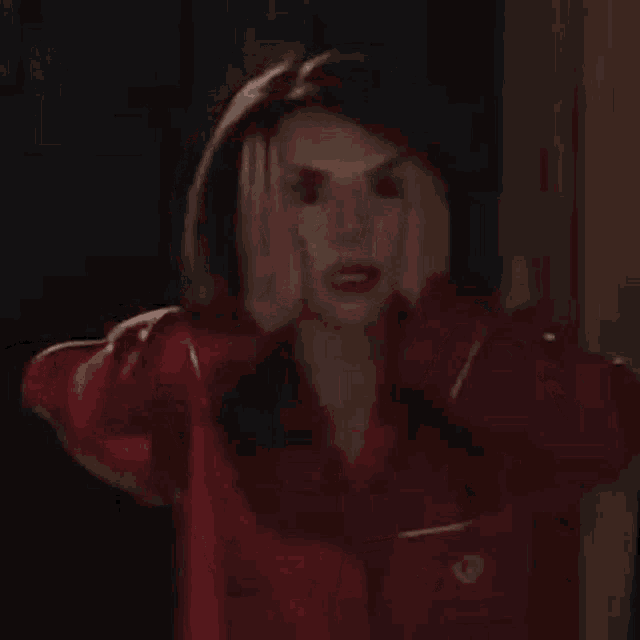 a woman in a red pajama shirt is holding her head in her hands .