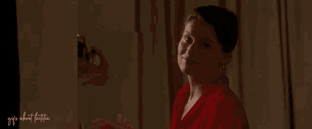 a woman in a red robe is standing in front of a mirror and clapping her hands .