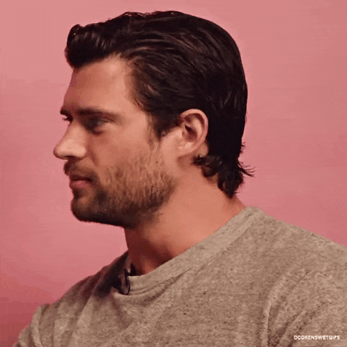 a man with a beard is wearing a grey shirt and looking to the side .