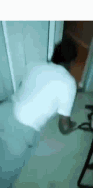a person in white pants is standing in a room with a chair .
