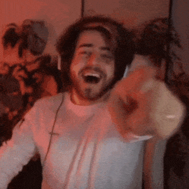 a man wearing headphones is laughing and pointing at the camera in a room .
