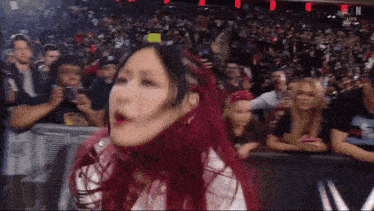 a woman with red hair is standing in front of a crowd and a sign that says kin live