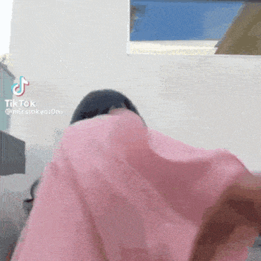 a tik tok video of a woman covering her face with a pink cloth .