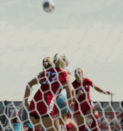 a soccer player with the number 32 on her jersey heads the ball