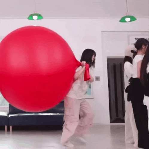 a woman is holding a large red balloon in her hands