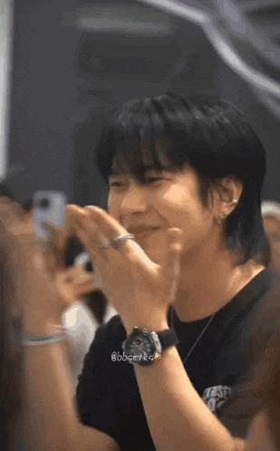 a man wearing a watch and a ring on his finger is smiling