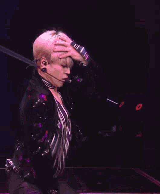 a man is holding his hand to his forehead while wearing a microphone