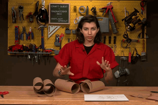 a woman in a red shirt stands in front of a craft quest sign