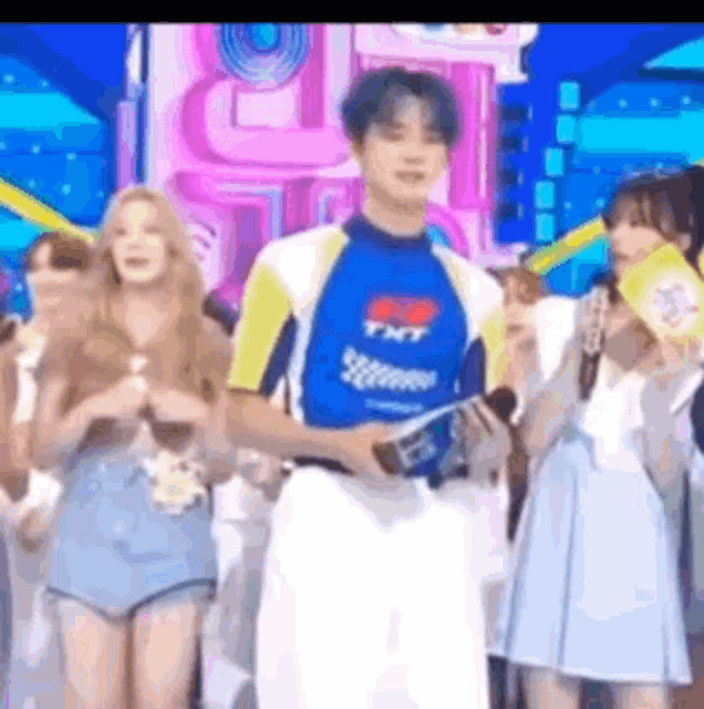 a man in a blue and yellow shirt is standing in front of a group of people on a stage .