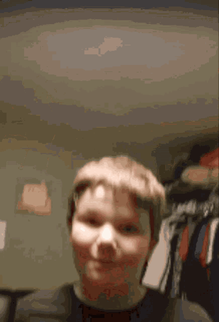 a young boy is standing in front of a closet with clothes hanging on the racks .