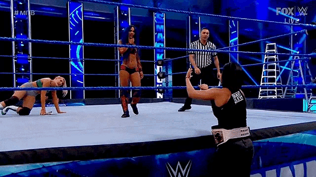 a woman is taking a picture of herself in a wrestling ring while a referee watches .