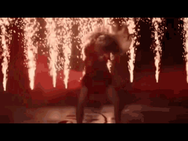 a woman is dancing on a stage in front of a fireworks display .
