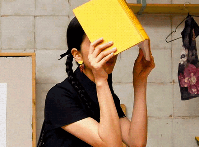 a woman covering her face with a book