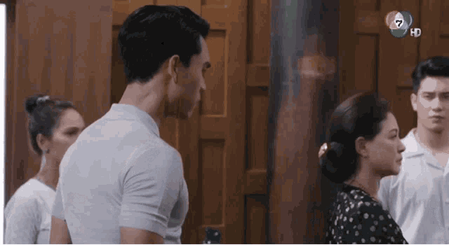 a group of people are standing in front of a wooden door and talking to each other .