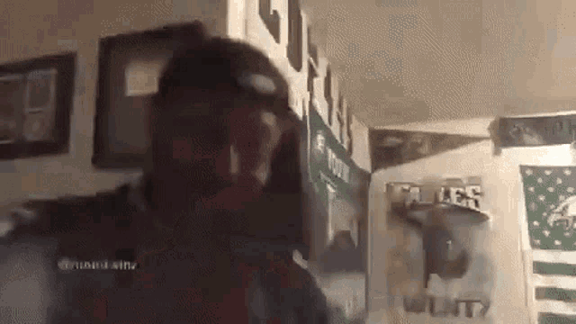 a man is standing in a room with a lot of posters on the walls .