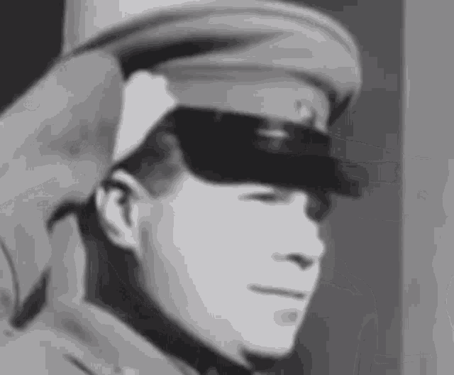 a black and white photo of a man wearing a military hat