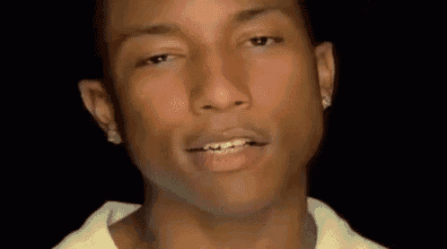 a close up of a man 's face with a black background . he is wearing a white shirt and earrings .