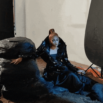 a woman in a black coat sits on a pile of rocks