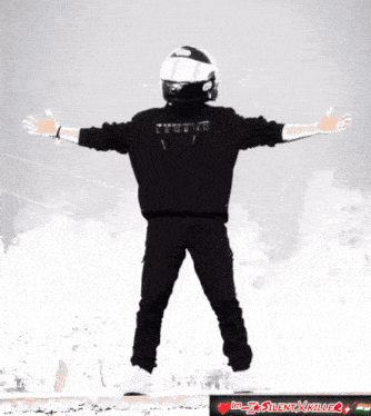 a man wearing a helmet stands with his arms outstretched in front of a sign that says im silent x killer