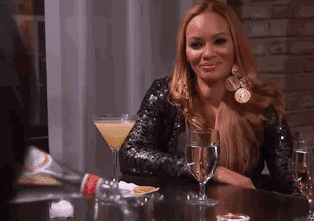 a woman sits at a table with a martini glass and a bottle of water