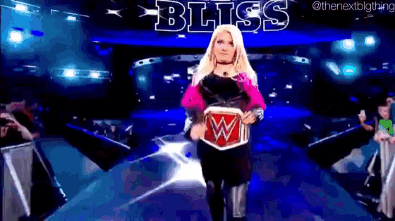 a woman is walking down a stage with a wrestling championship belt .