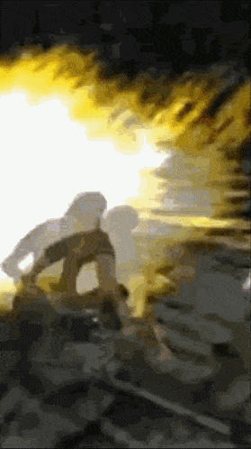 a blurry picture of a person standing in a dark room with a fire coming out of the ceiling .