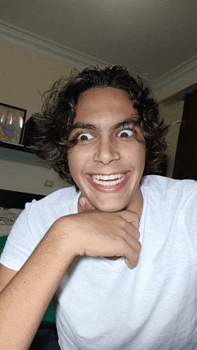 a young man with curly hair and braces on his teeth makes a funny face