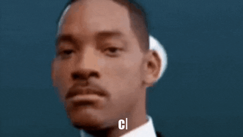 a man in a suit and tie is adjusting his glasses with the letter c above him