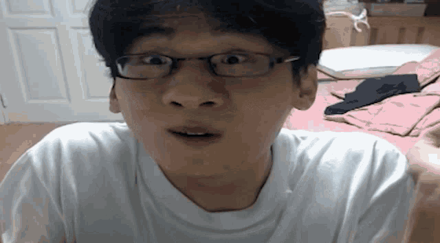 a man wearing glasses and a white shirt is making a funny face