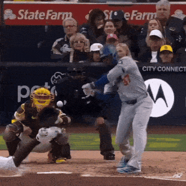 a baseball player swings at a pitch in front of a state farm banner