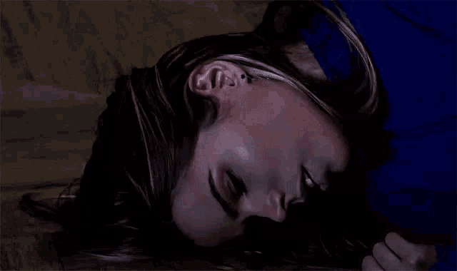 a woman is laying on her back with her eyes closed and a man is touching her face .