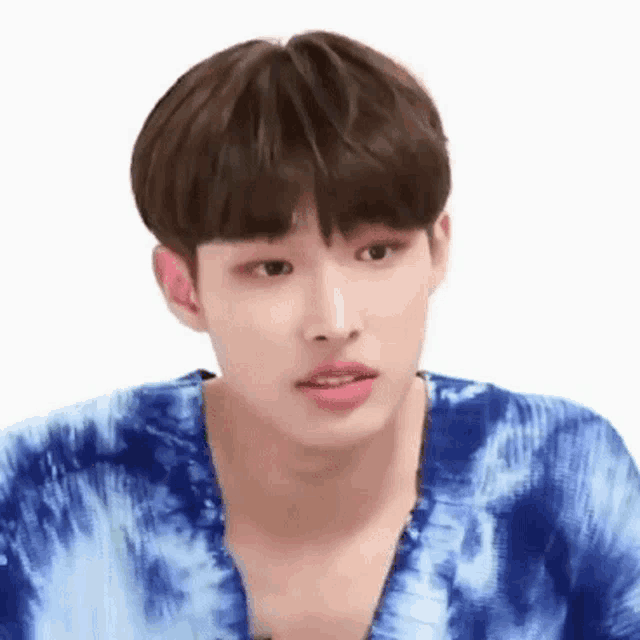 a young man wearing a blue tie dye shirt is looking at the camera .