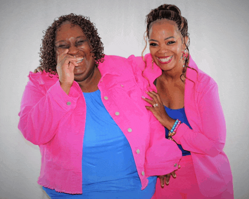two women wearing bright pink jackets are posing for a photo