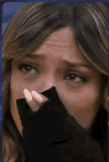 a woman is crying and covering her face with her hand .