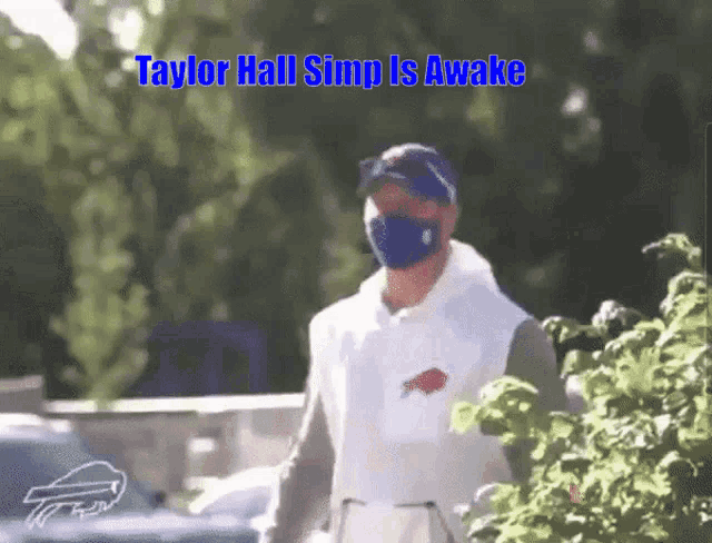 a man wearing a mask and a buffalo bills shirt is walking down the street