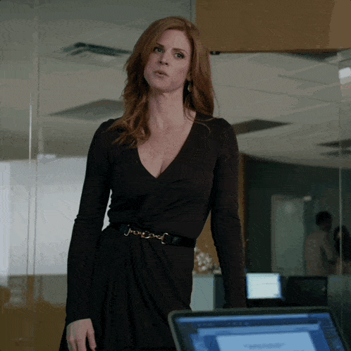 a woman in a black dress is standing next to a laptop
