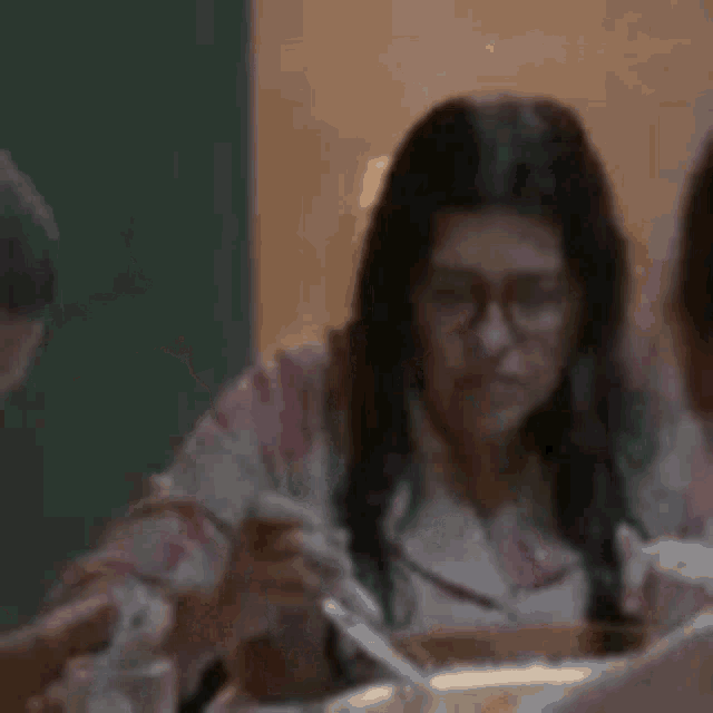 a woman is sitting at a table with her hands in the air .