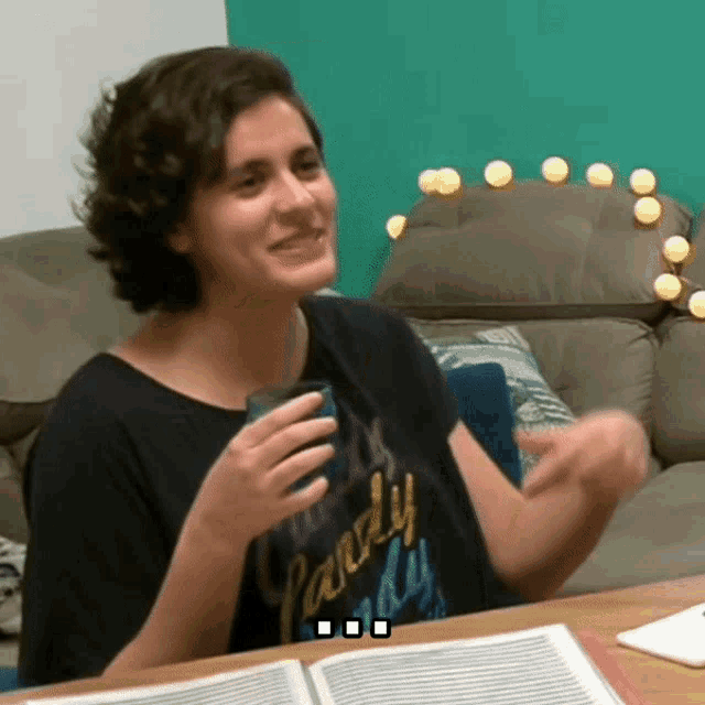 a woman sitting at a table wearing a shirt that says " candy "