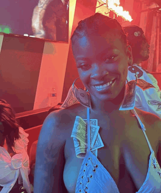 a woman wearing a white top with a dollar bill hanging from her bra