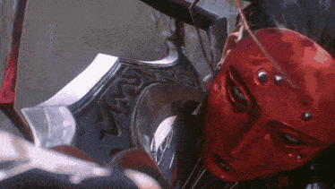 a close up of a red mask with a sword