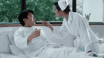 a nurse is pointing at a patient laying in a hospital bed