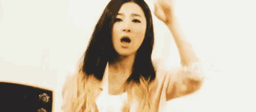 a woman with long hair is holding her hand to her forehead and making a funny face .