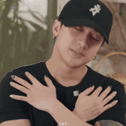 a man wearing a black hat and a black shirt has his hands folded in front of his chest