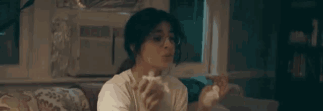 a woman is sitting on a couch eating popcorn and says eu falando com a tv .