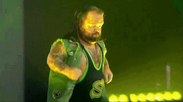 a wrestler in a green and black outfit with the letter s on it