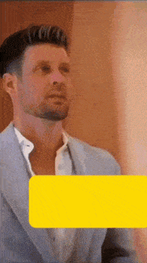 a man in a suit and white shirt is standing in front of a yellow box .